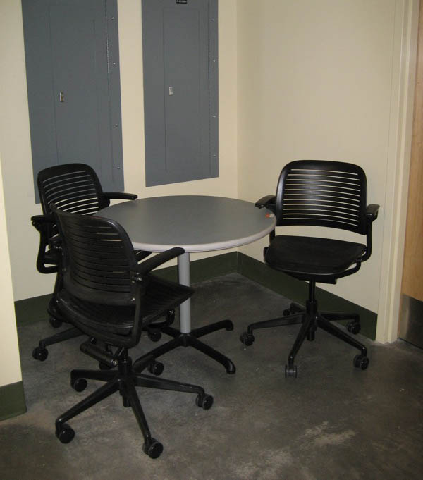 Cramped learning space: three chairs around a circular table crammed into a corner