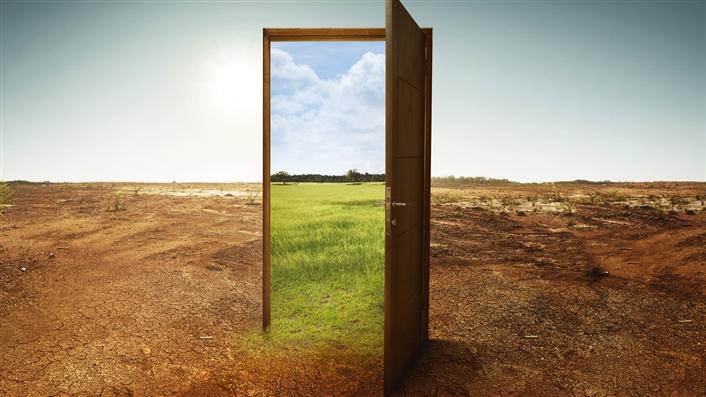 photo of open door in empty barren field looking through to a green version of the same landscape