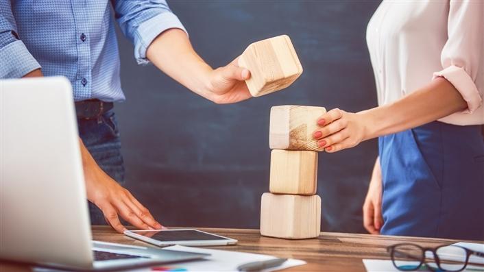 photo of two people stacking wooden blocks on a table