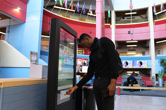 a student using the kiosk with the rotunda in the background.