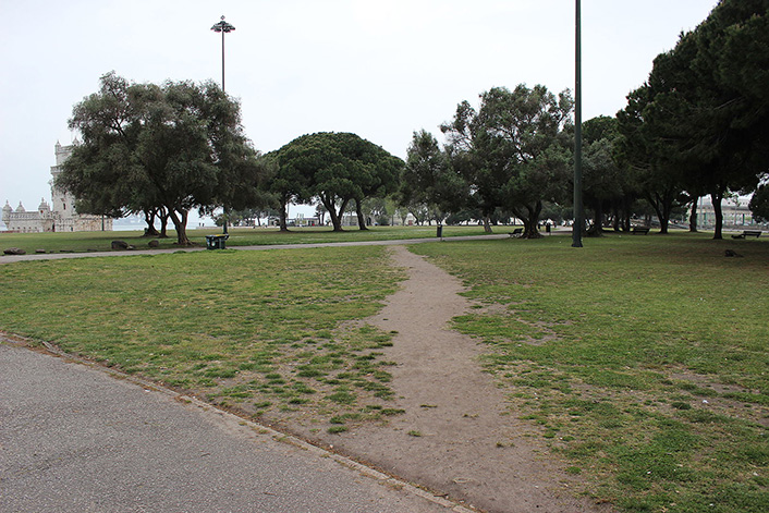 image of a lawn bordered on two sides by concrete paths.  There is a dirt path through the grass cutting the corner between the two concrete paths.