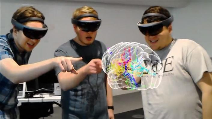 photo of three students looking at a human brain model through VR headsets