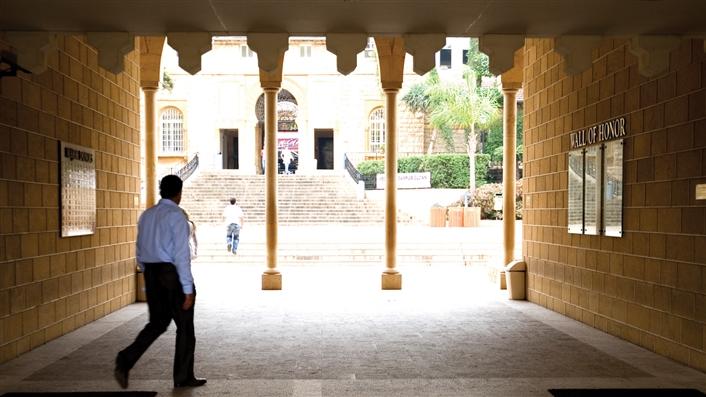 Man walking through pillared corridor