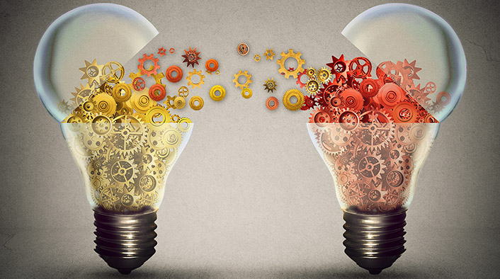 Two lightbulbs filled with gears - one bulb has gold gears and the other has red. The top of each bulb is open and the gears are crossing over between them and mixing together.