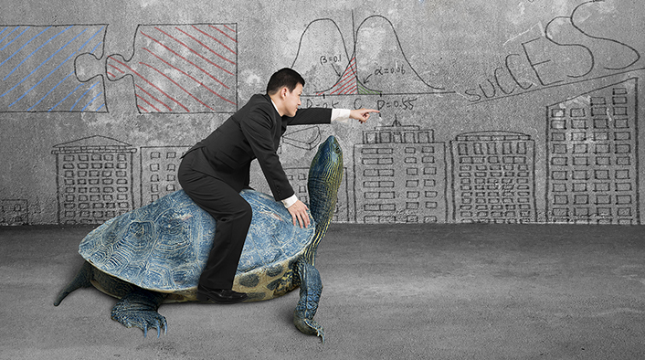Businessman riding turtle and indicating with finger in a concrete room with business concept doodles wall background