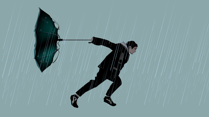 person walking through rain and leaning into the wind with an inverted umbrella behind them