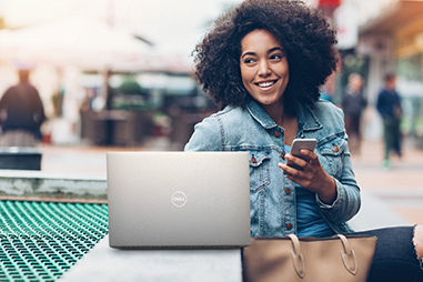 Woman sitting in an open indoor area using a laptop and phone