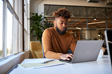 Man sitting inside at a table using a laptop