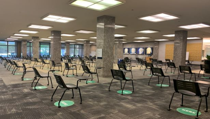 Large room with individual chairs with attached desk facing the front of the room.