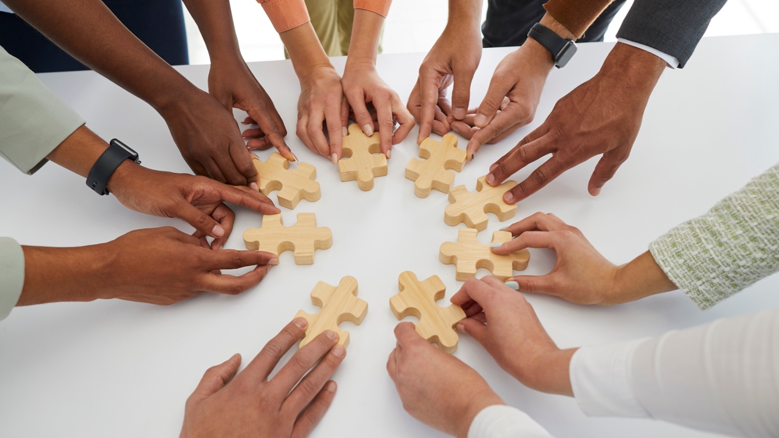 circle of hands each holding a puzzle piece