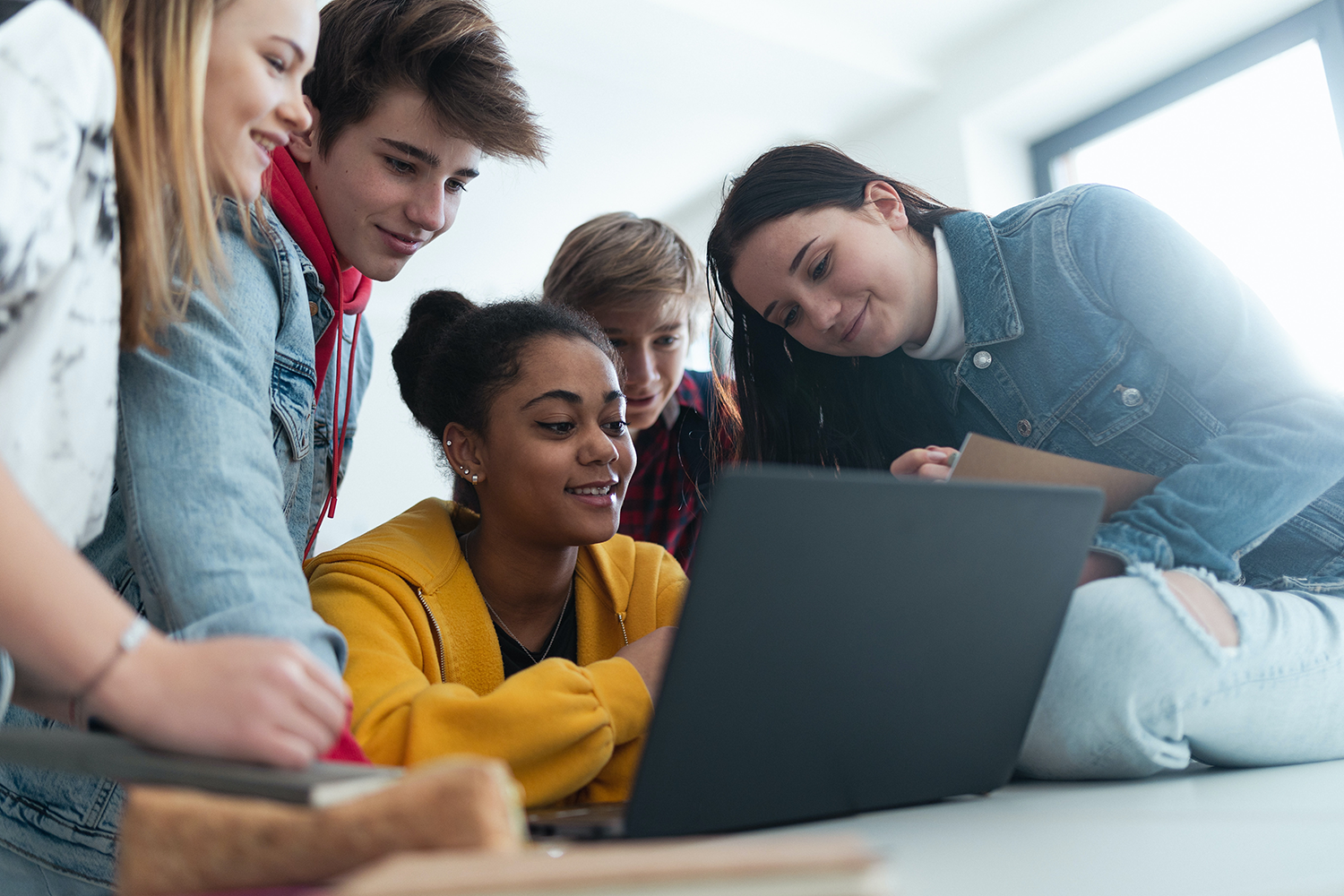 Group of students crowded around one laptop.