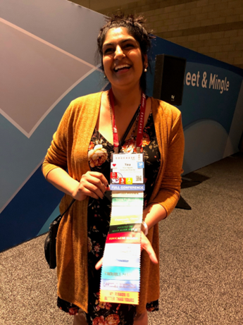 Woman showing conference badge with a string of ribbons on it.