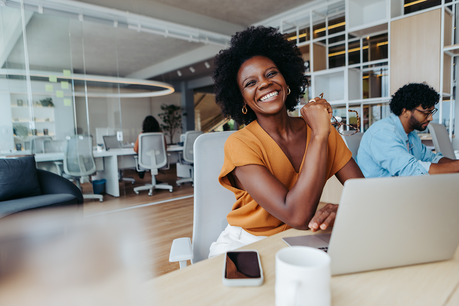 Woman smiling broadly while sitting in front of a laptop computer