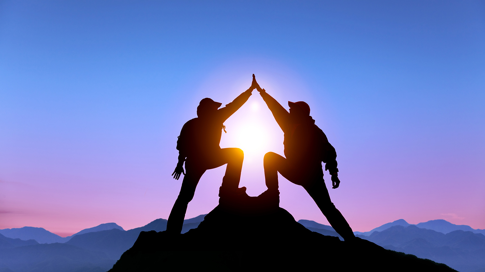 Two people high fiving at the top of a peak