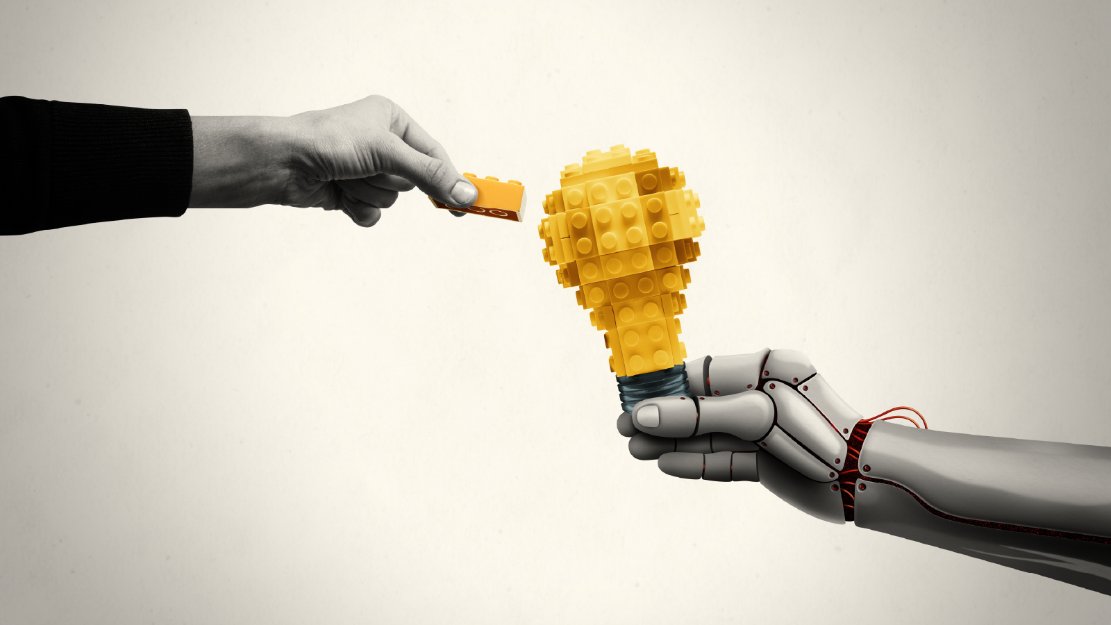 A human hand passes a yellow block to a robotic hand holding a block-built lightbulb