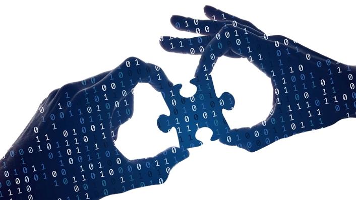image of two hands holding a jigsaw puzzle piece with zeros and ones overlaid on them