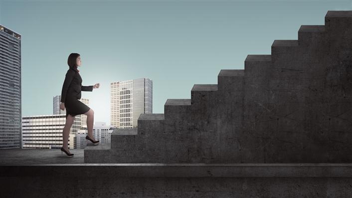 picture of woman taking first step up a flight of stairs with city skyline in the background