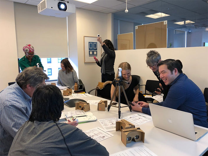 8 people around a table. They are collaborating in groups of 2 or 3.