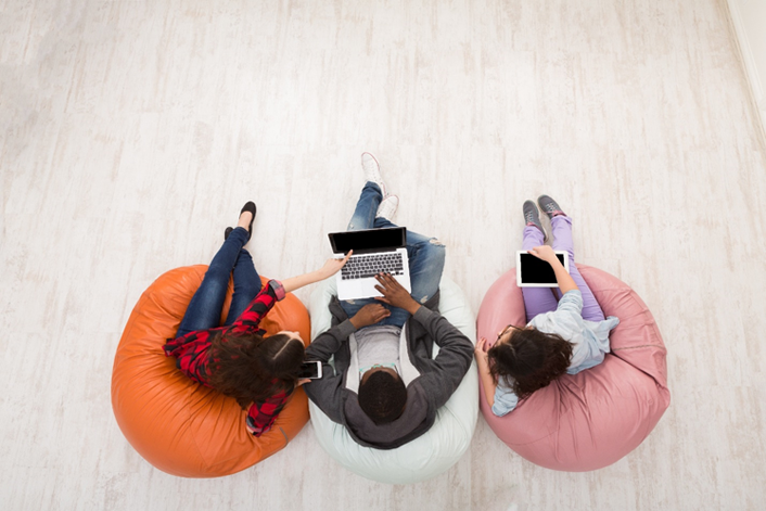 overhead photo of three students in bean bag chairs working on a laptop