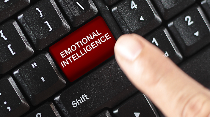 Finger hovering over a key on a keyboard. The key is labelled Emotional Intelligence.