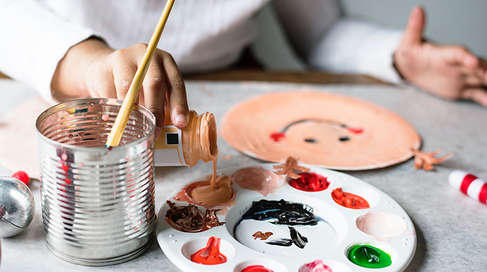 hand pouring paint from a jar onto a palette