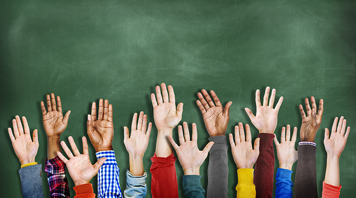 image of the forearms and hands of people holding them up in the air against a green backdrop