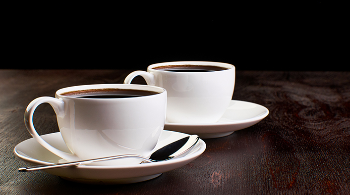 two white saucers, a spoon, and cups of espresso