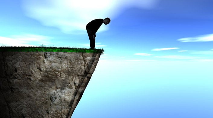A man peering over the edge of a cliff