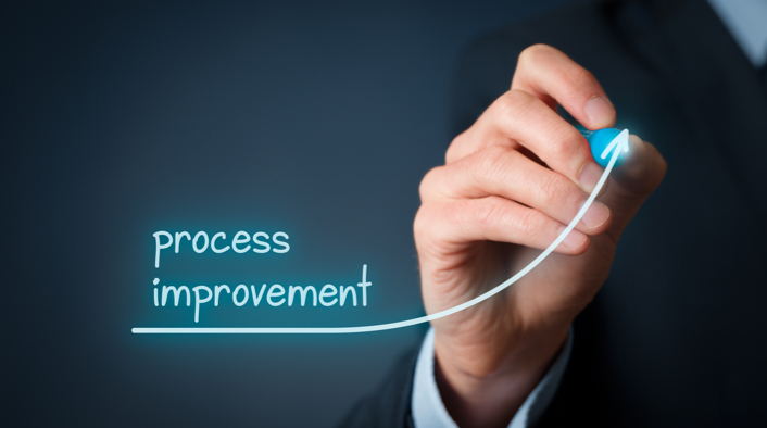 person writing "process improvement" underlined by an ascending arrow on a screen