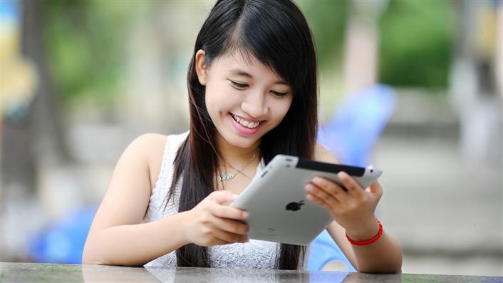 Asian woman smiling while working on an iPad