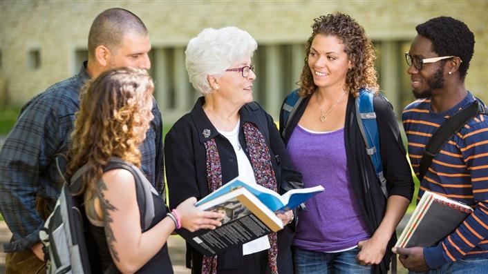 Four college students being mentored by an older, female, college professor